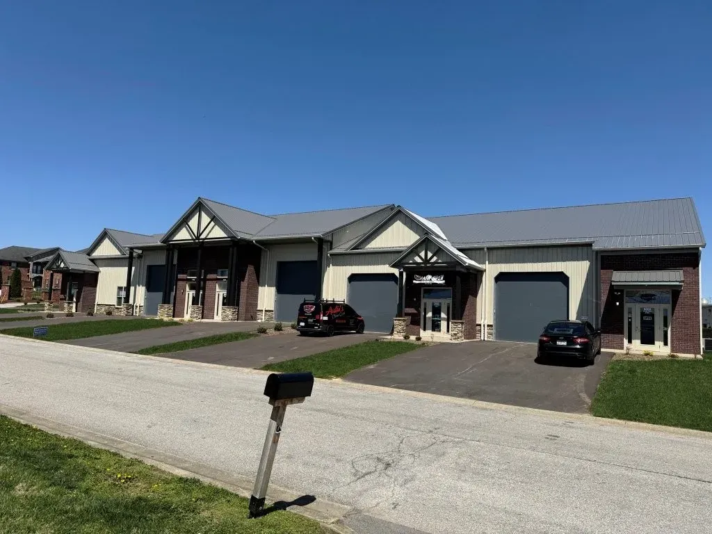 Office-warehouse building frontage with separate office entry doors, overhead doors, and paved driveways