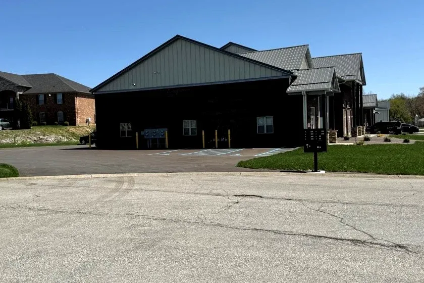Side of an office-warehouse building with brick and metal siding, mailboxes, and a paved lot
